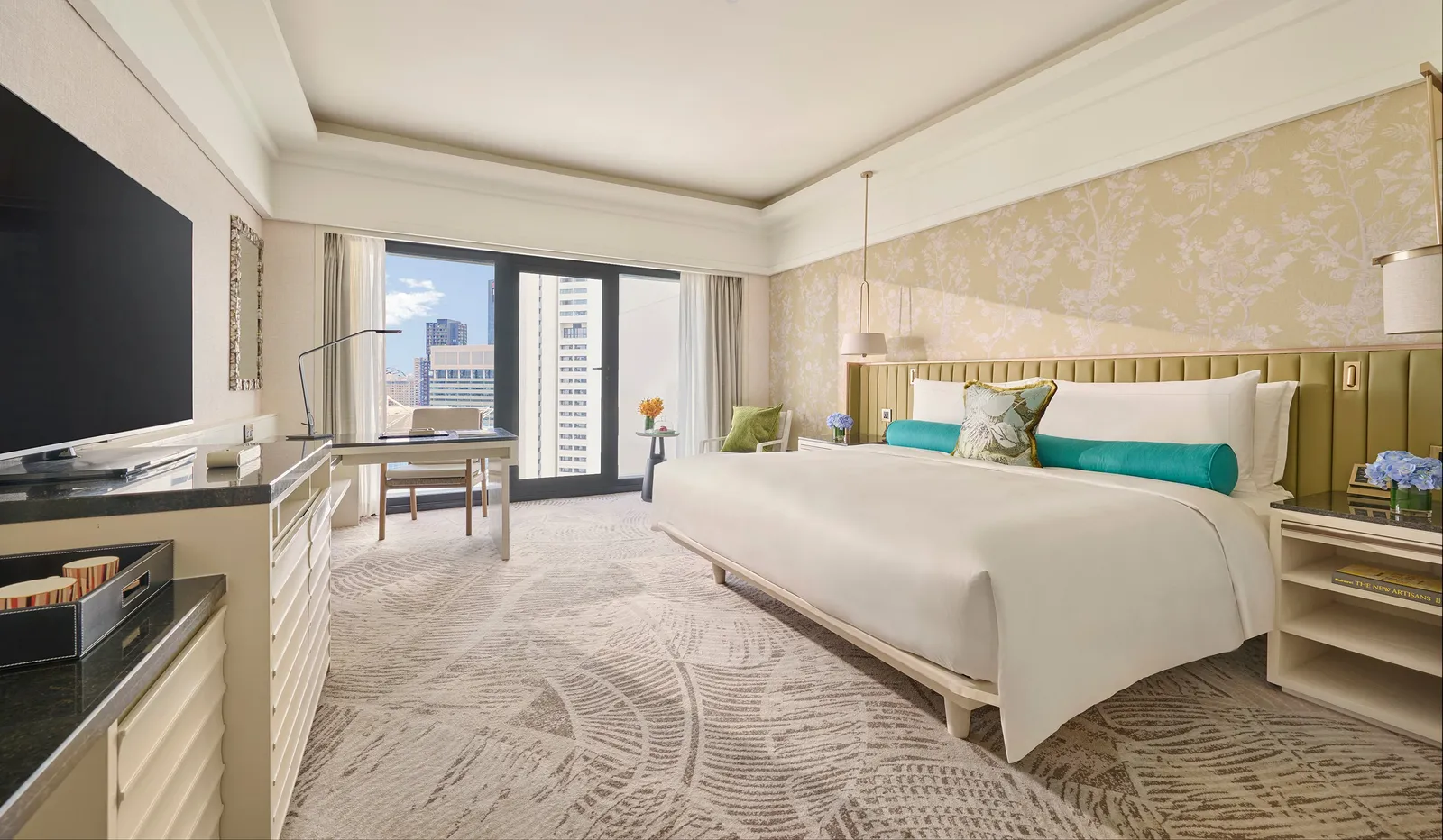 The Deluxe Room: the bed with turquoise bolsters, the desk and the window onto the city.