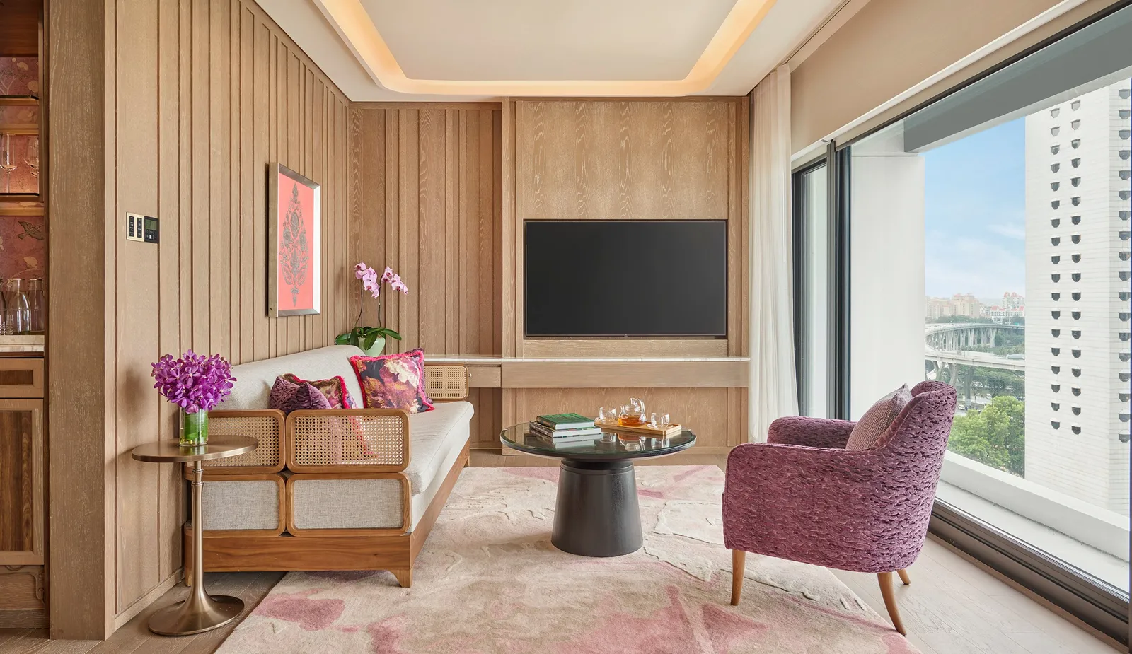 The living room of the Sea View Suite with Balcony: a rattan sofa, a purple armchair and the window to the balcony.