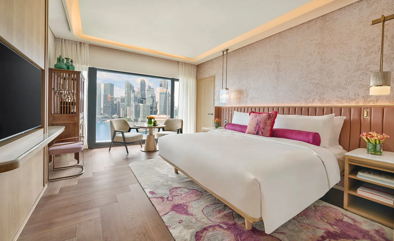 A connecting bedroom of the Three Bedroom Presidential Suite: the bed with fuchsia cushions, a floral rug and the towers in the window.