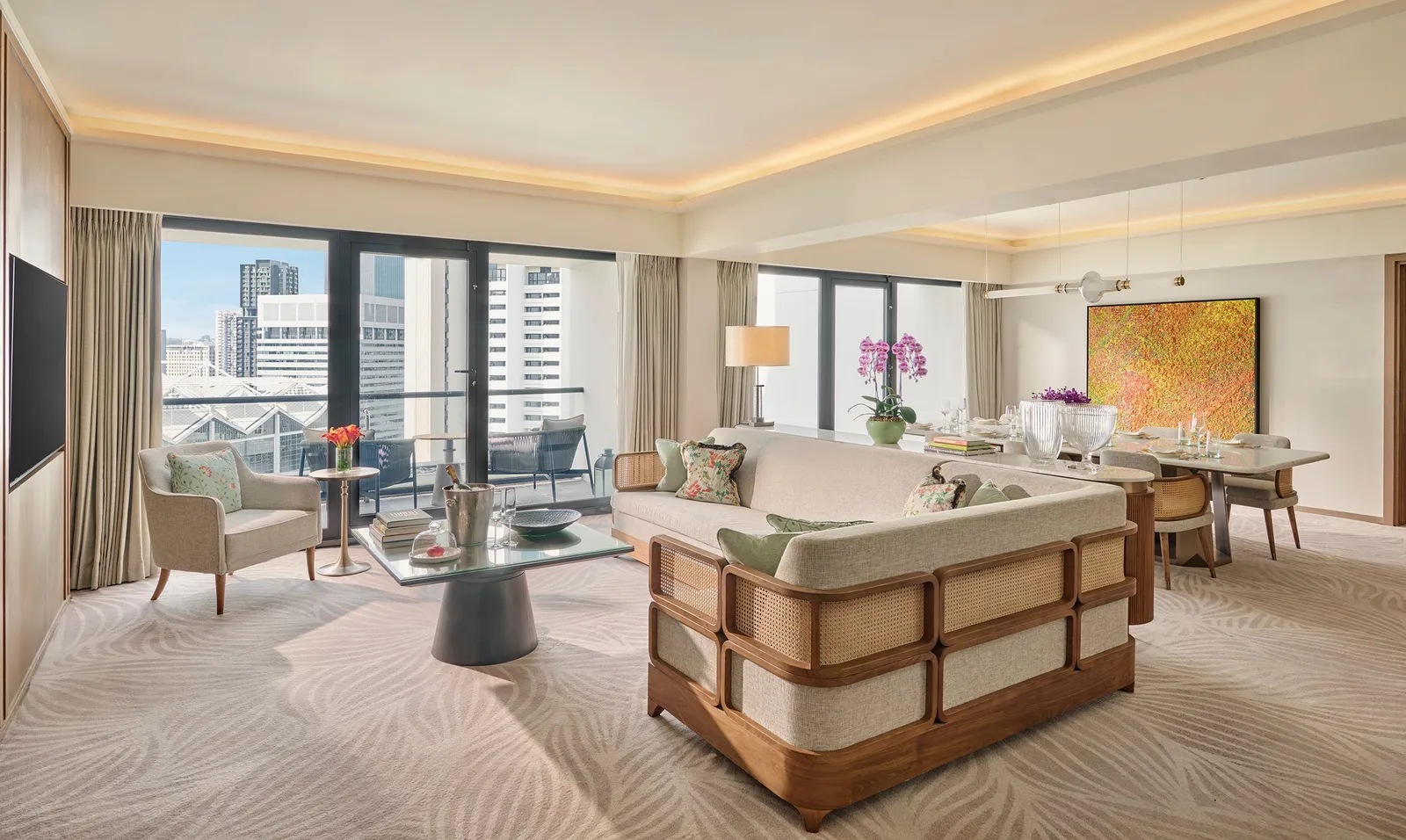 The living room of the Three Bedroom Residential Suite: a sofa, the dining table laid and the balcony over the city.