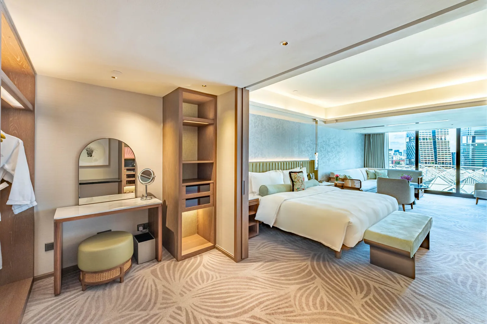 The main bedroom of the Two-Bedroom Premier Family Suite: a dressing table with an arched mirror and the bed facing the window onto the city.