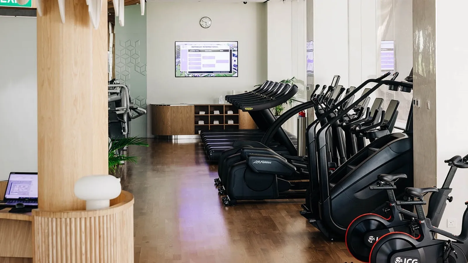 The gym: treadmills, cross-trainers and bikes in a row on a timber floor.