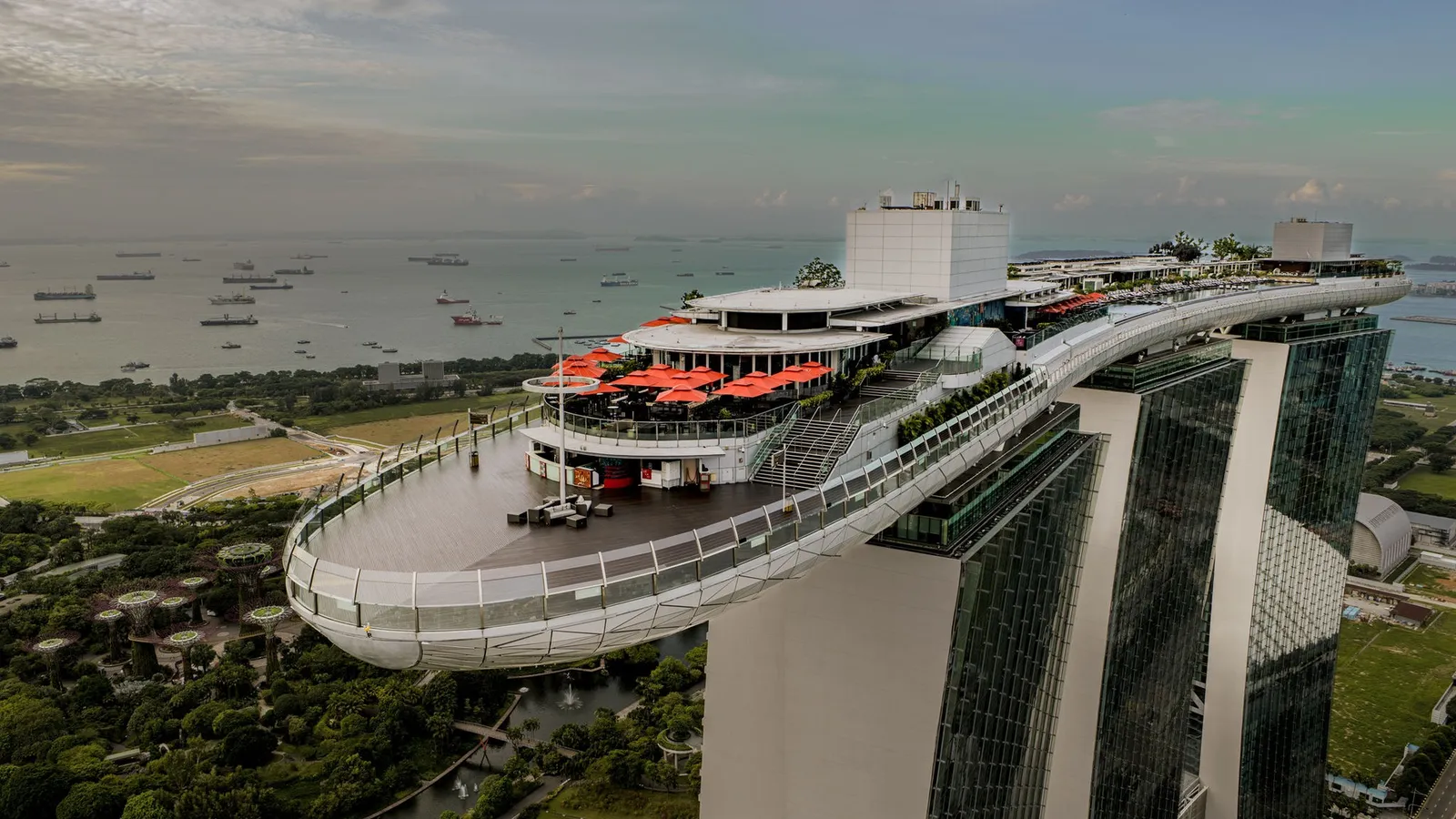 The tip of the SkyPark jutting past the tower: the timber observation deck, a restaurant’s red parasols and, beyond, ships in the strait.