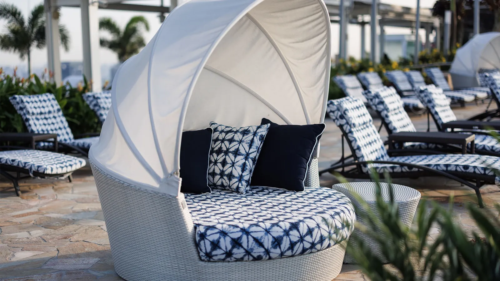 A white shell-shaped daybed among the loungers on the pool deck.