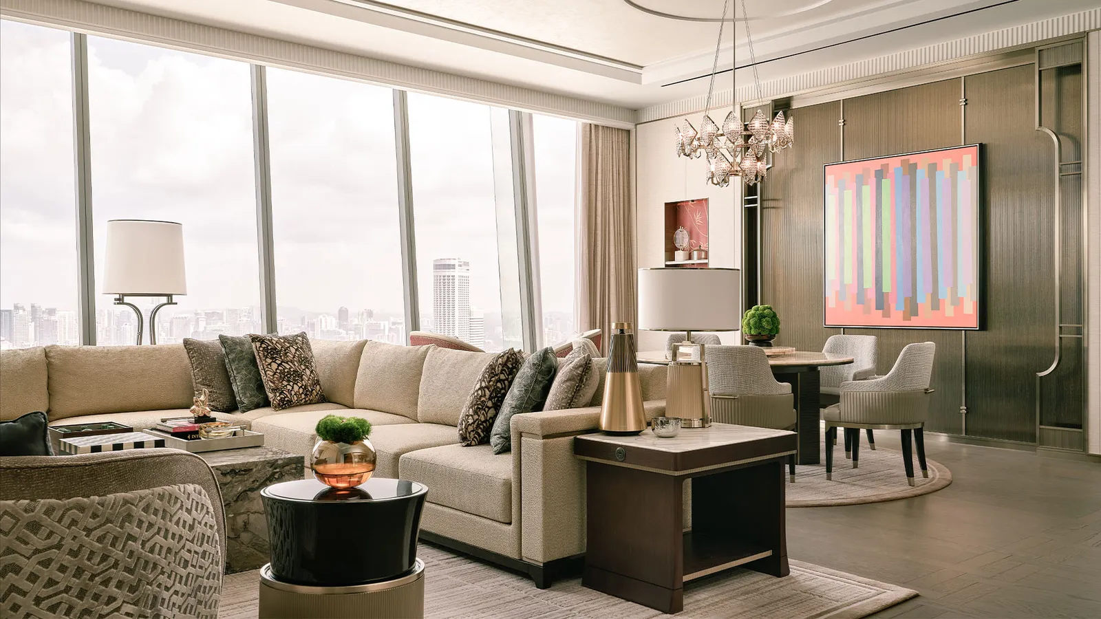 Merlion Suite: the sitting room with a corner sofa and the dining area, windows on the city.