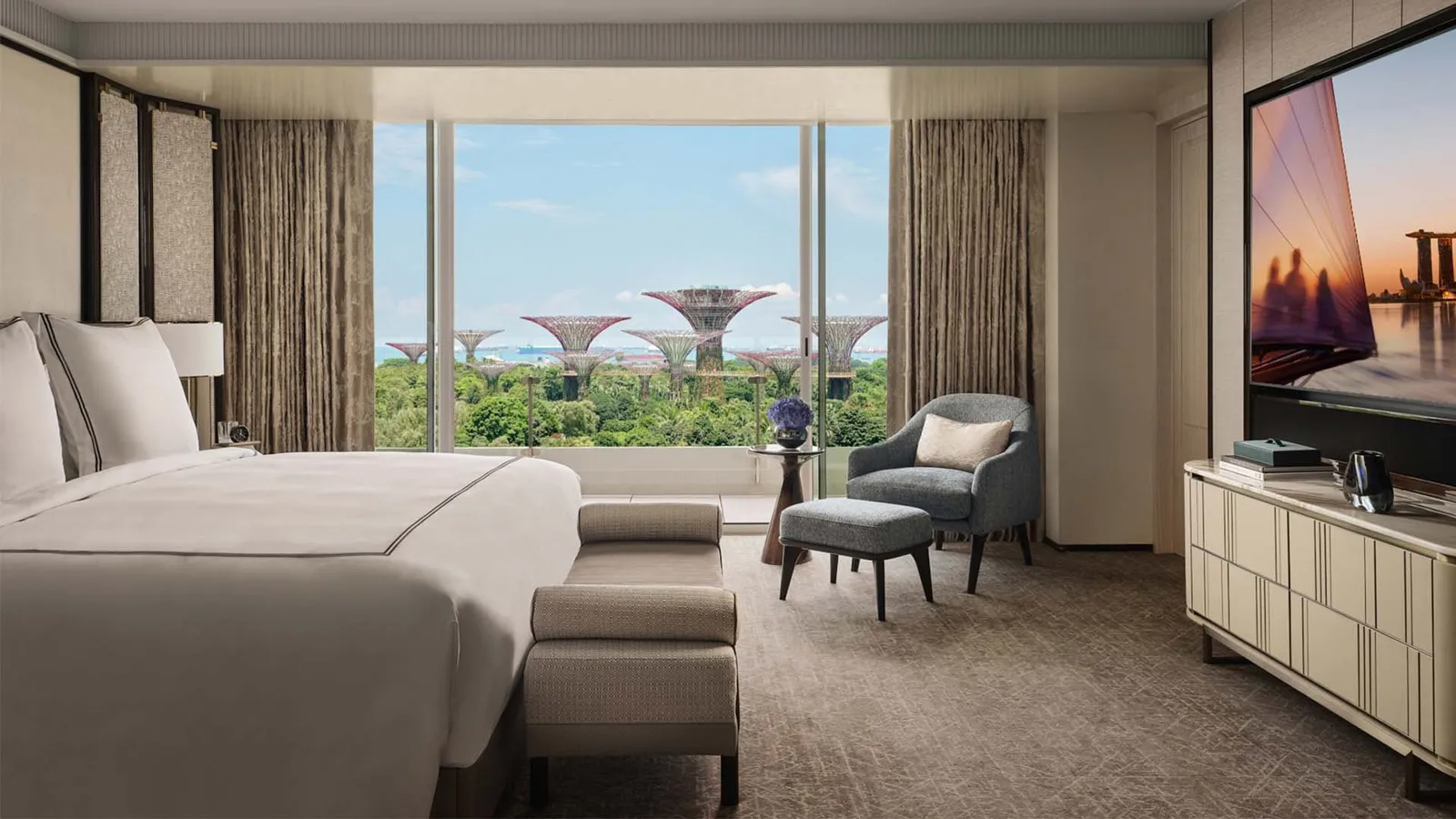 Sands Premier Suite: the bedroom with its bed, an armchair and the Supertrees beyond the window.