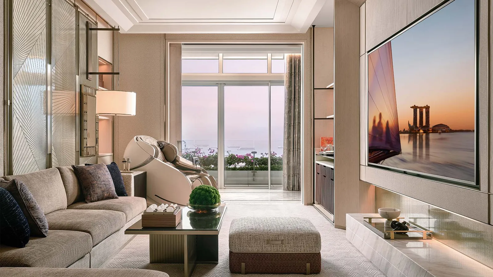 Straits Suite: the sitting room with a massage chair and the window on the sea at sunset.