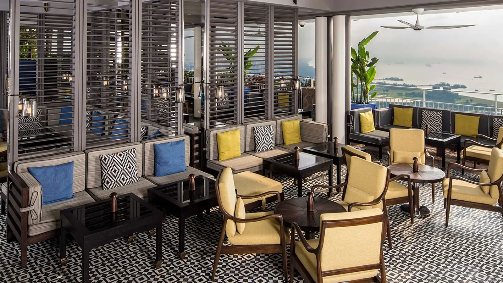 The terrace of Spago Bar & Lounge: yellow armchairs, sofas and black-and-white tiles, the sea beyond the shutters.
