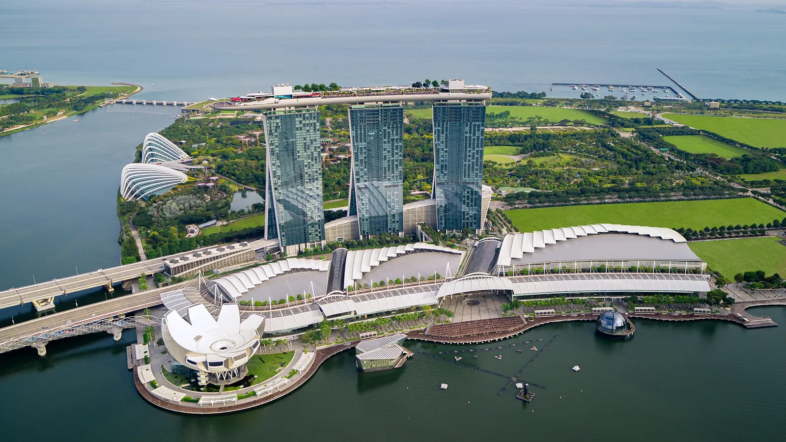 The complex from the air: the 3 towers, the mall and the lotus-shaped museum on the bay, the gardens and the sea behind.
