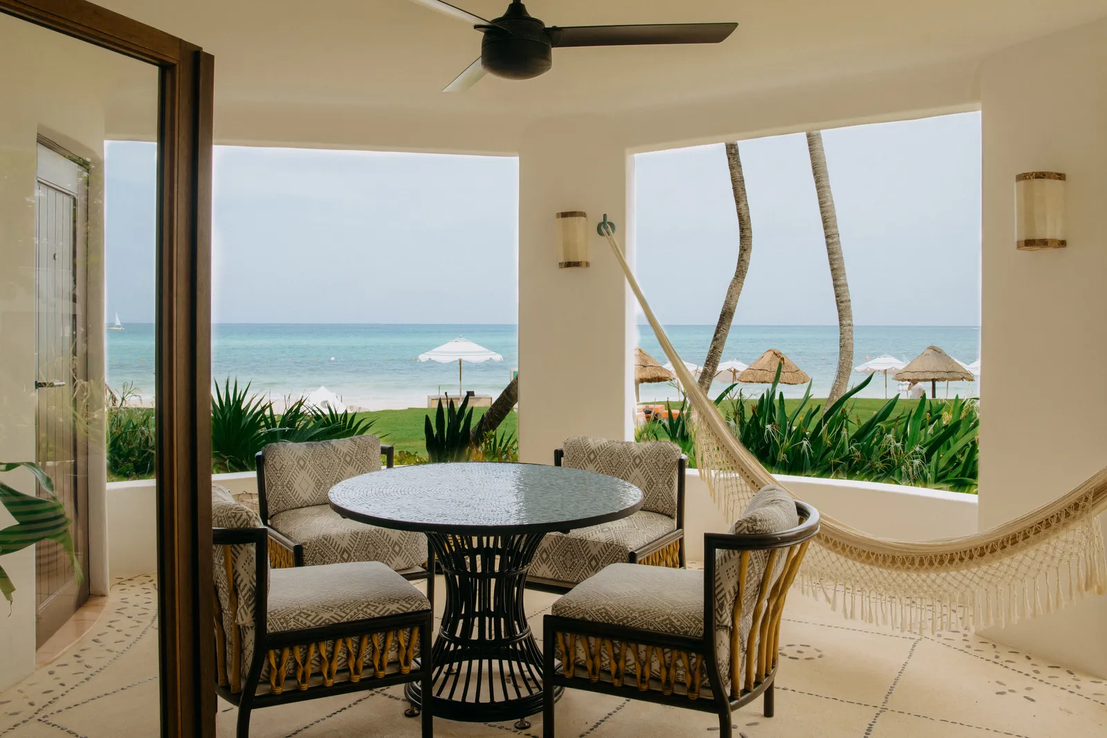 L’amaca sulla terrazza della Ocean View Junior Suite, con un tavolo e il mare oltre le palme