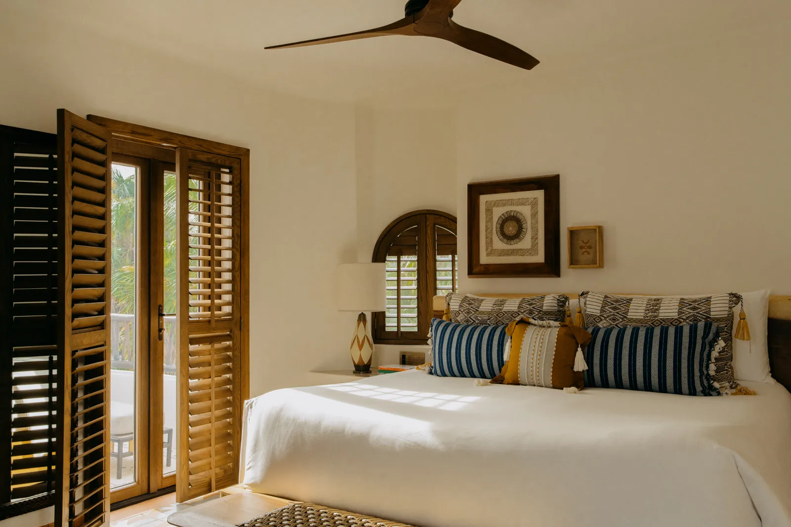 Il letto king della Ocean View Suite fra persiane di legno e cuscini a righe blu