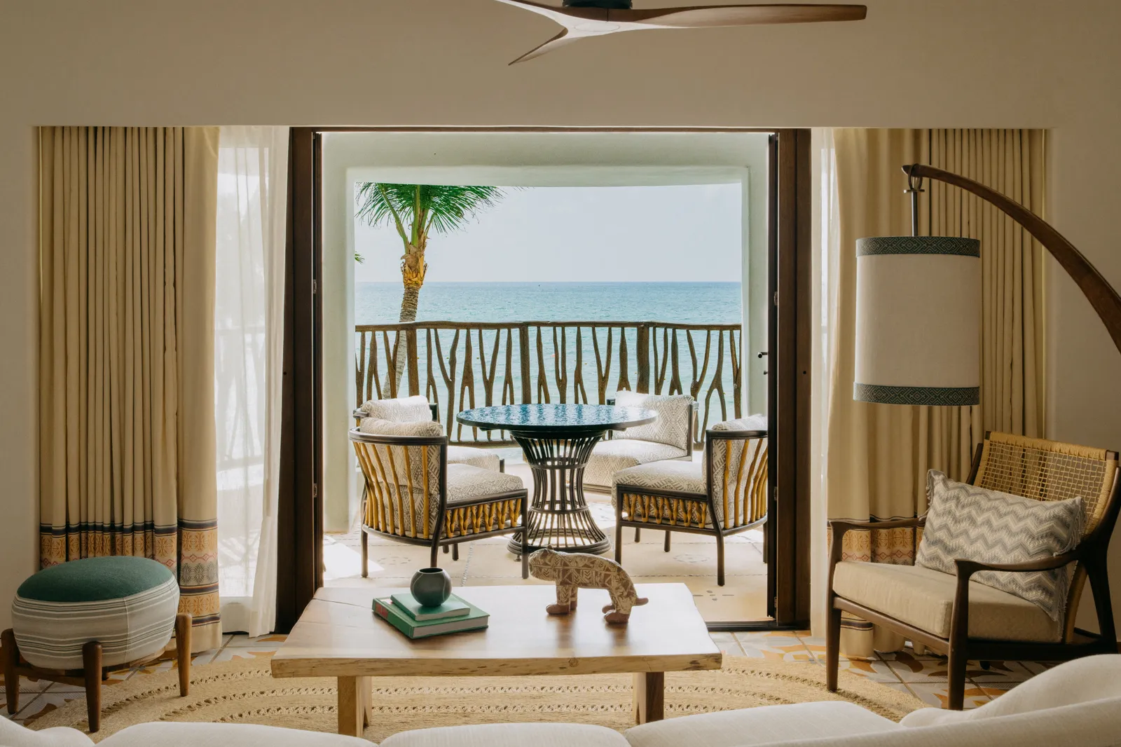 Il letto della suite Oceanfront con piscina, davanti alle porte aperte sulla terrazza con poltrone di vimini