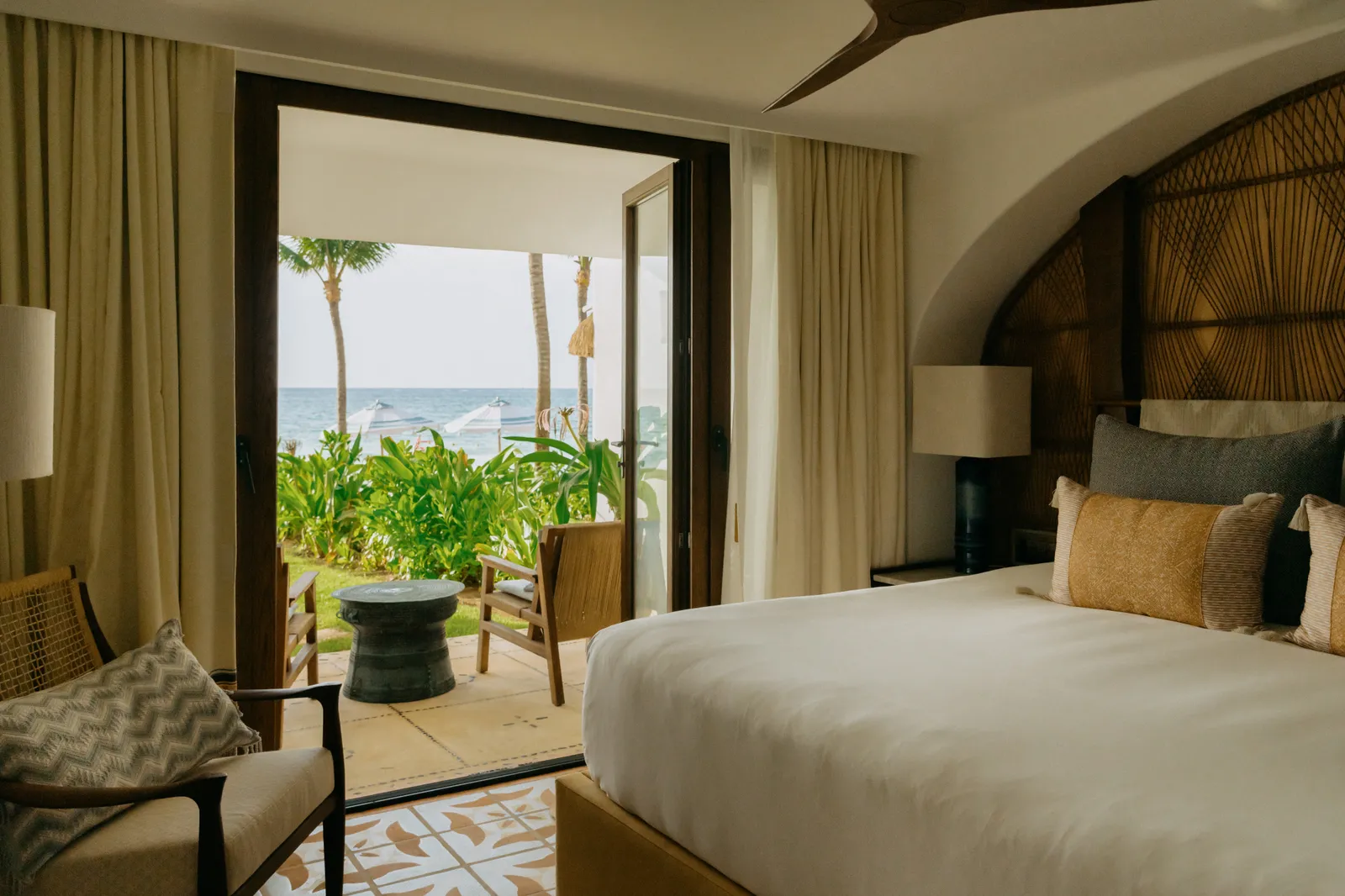Una camera di Villa Mariposa con le tende aperte sulle palme e la terrazza