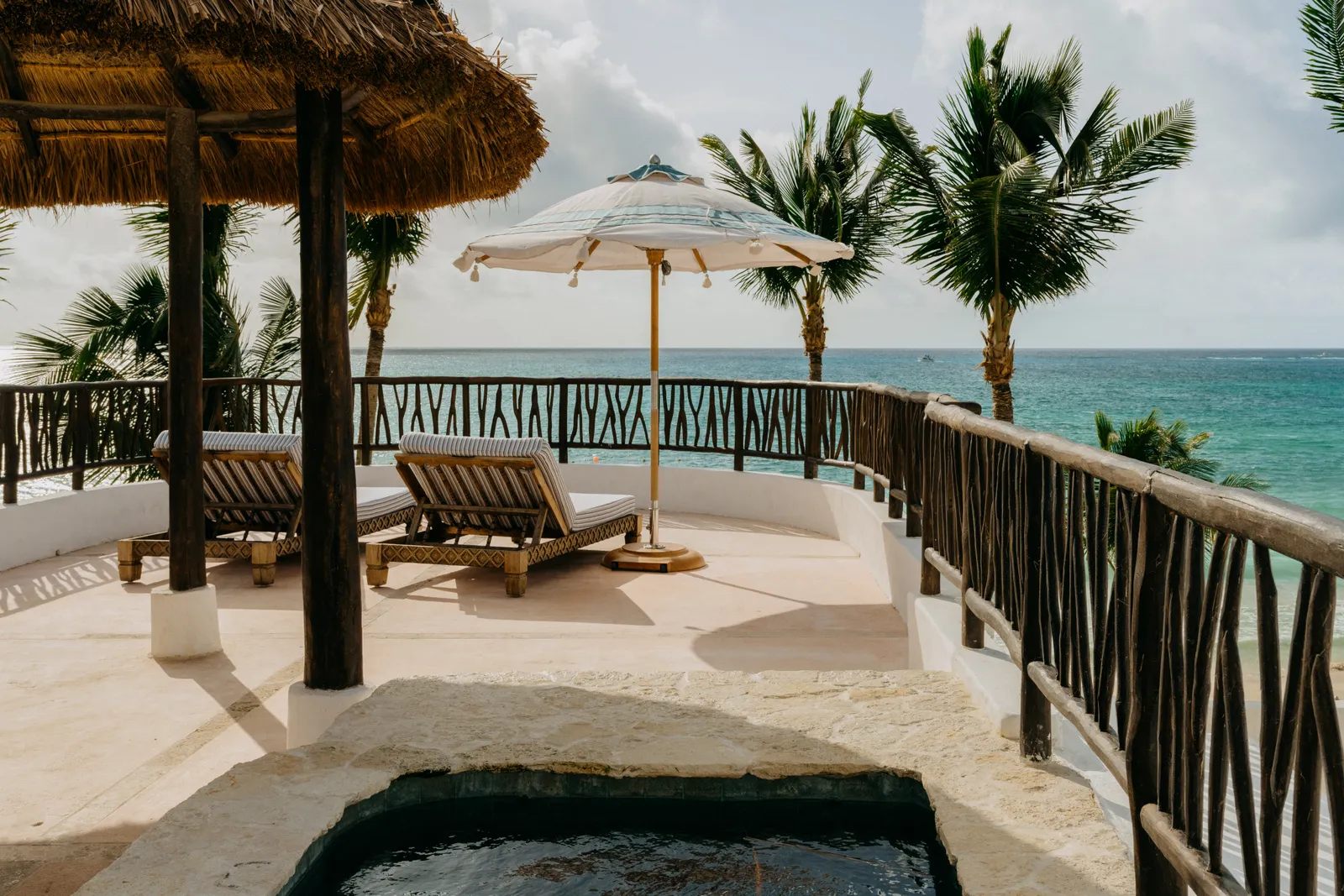 La terrazza di Villa Xuxú: una vasca privata e i lettini dietro la ringhiera di legno sul mare
