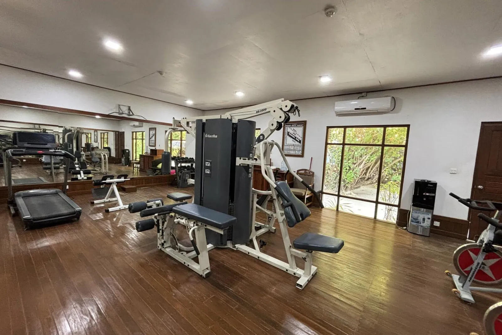The gym with its wooden floor, weight machines, a treadmill and an exercise bike.