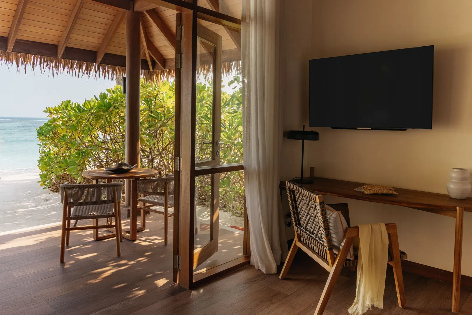 Inside a Sunrise Beach Villa: the desk, the television and the doors open onto the thatched terrace.