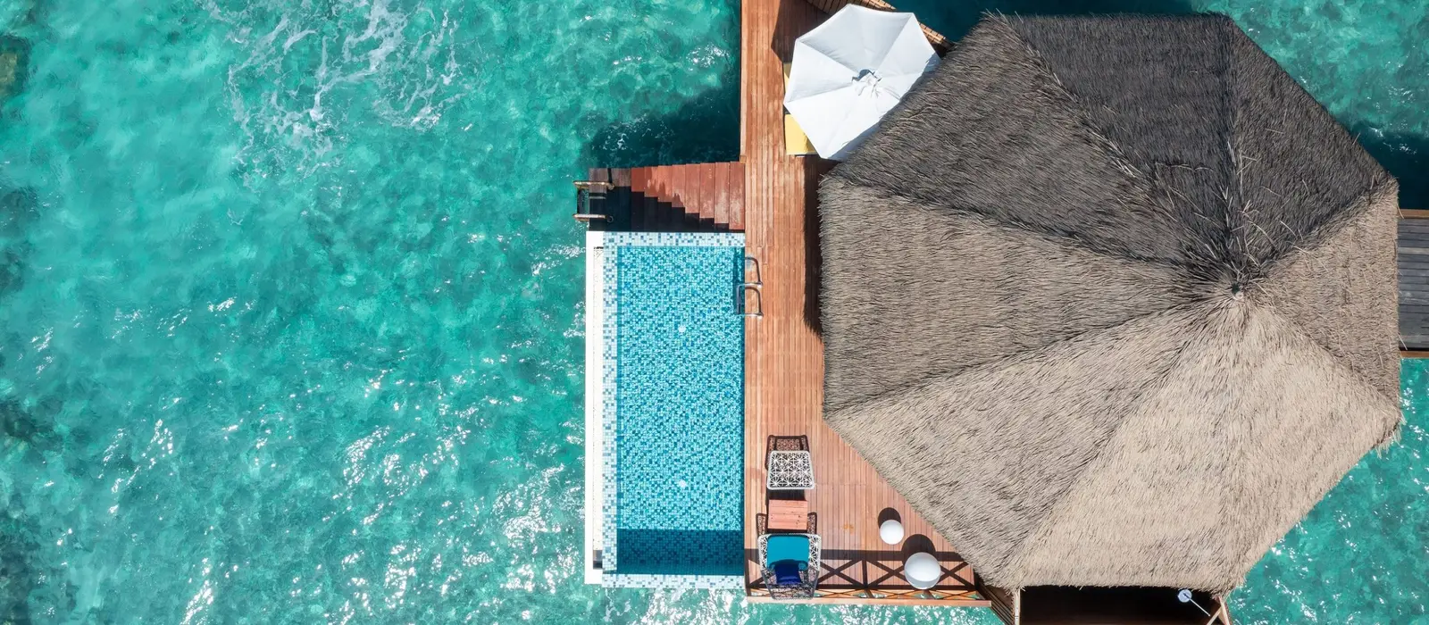 An Overwater Reef Pool Villa from above: the thatched roof, the pool on the deck and the reef all round.
