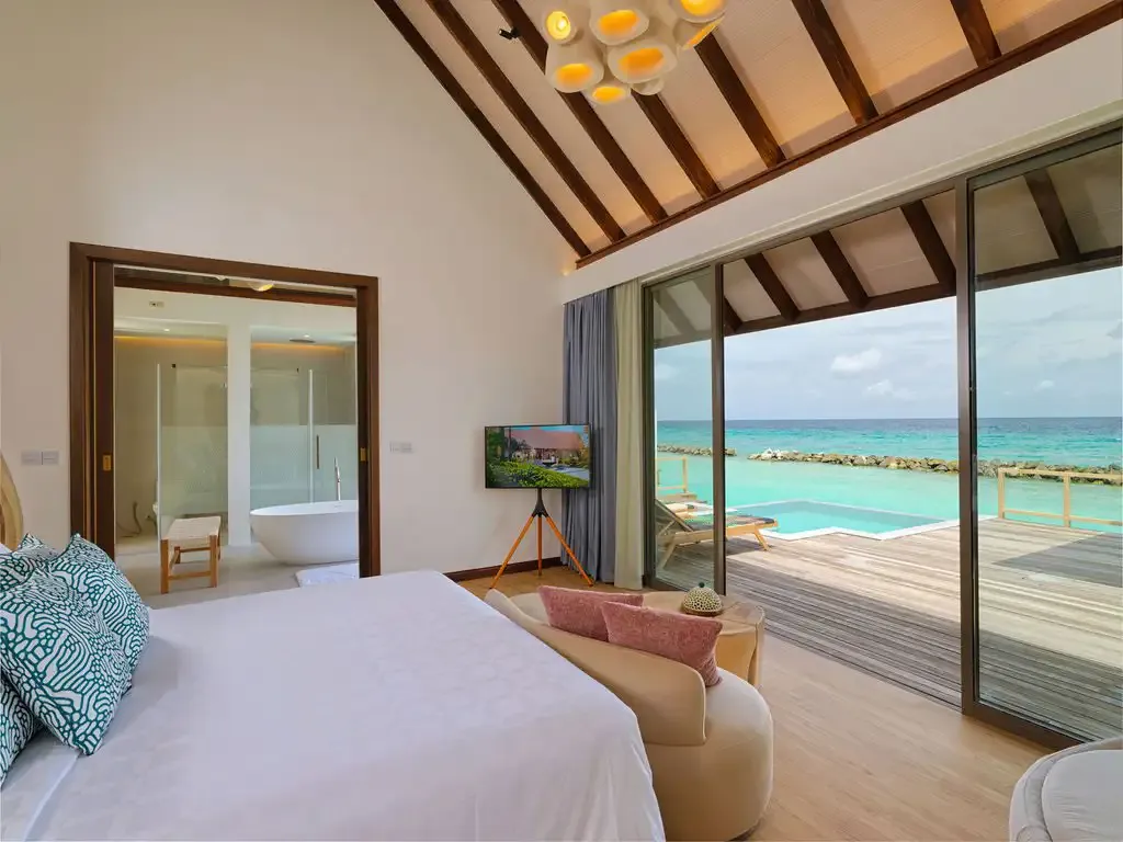The bedroom with its bed and a door towards the bathroom.