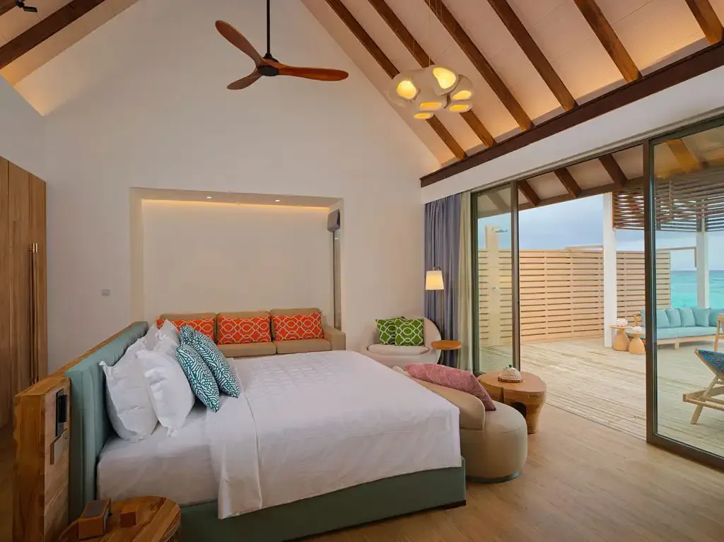 The bedroom with its bed and seating by the glass doors.