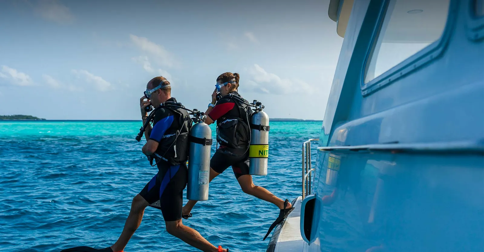 2 divers stepping off the boat into the open sea