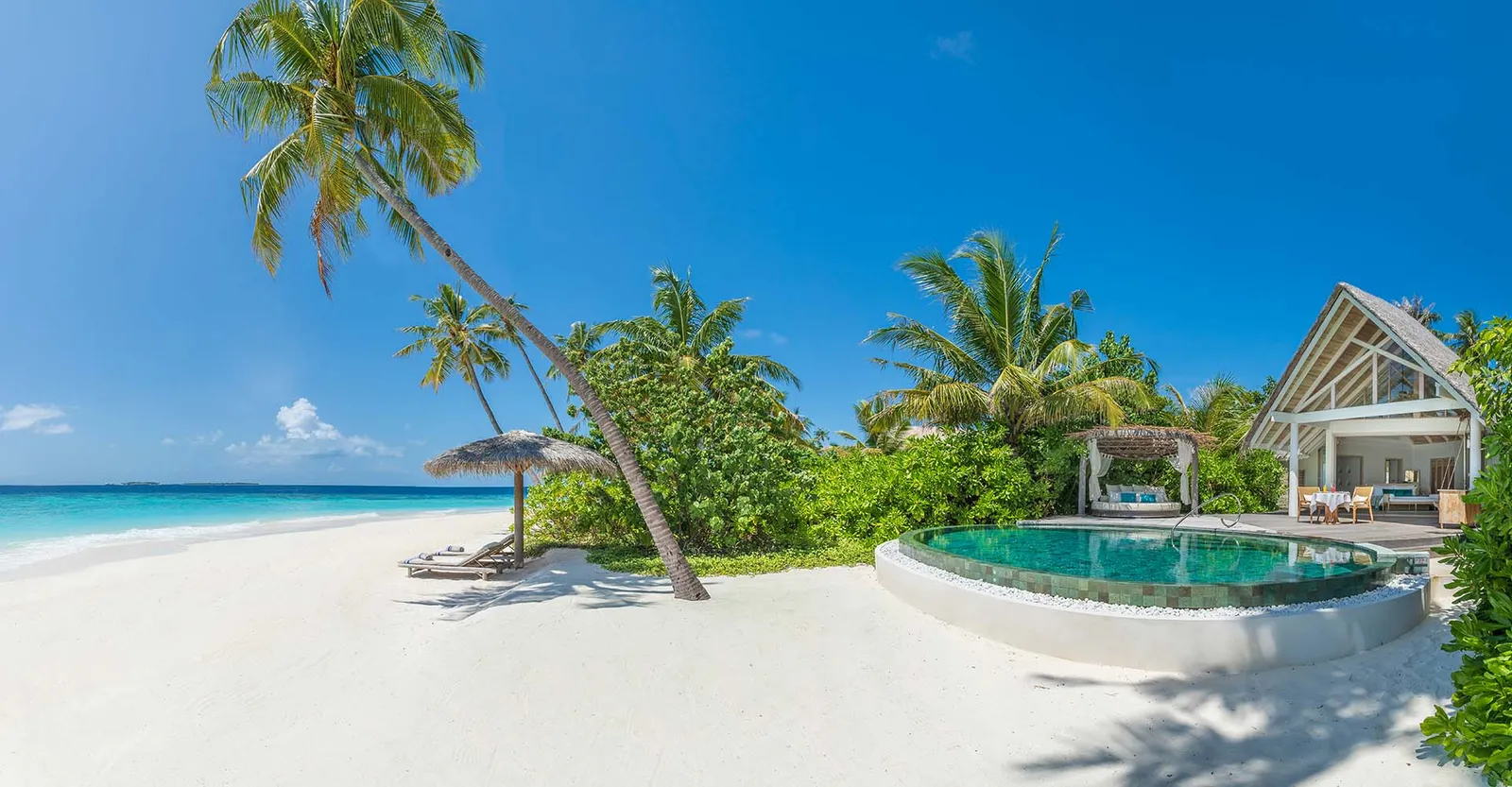 A Beach Pool Villa: the round pool on the sand, the palms and the steep-roofed villa
