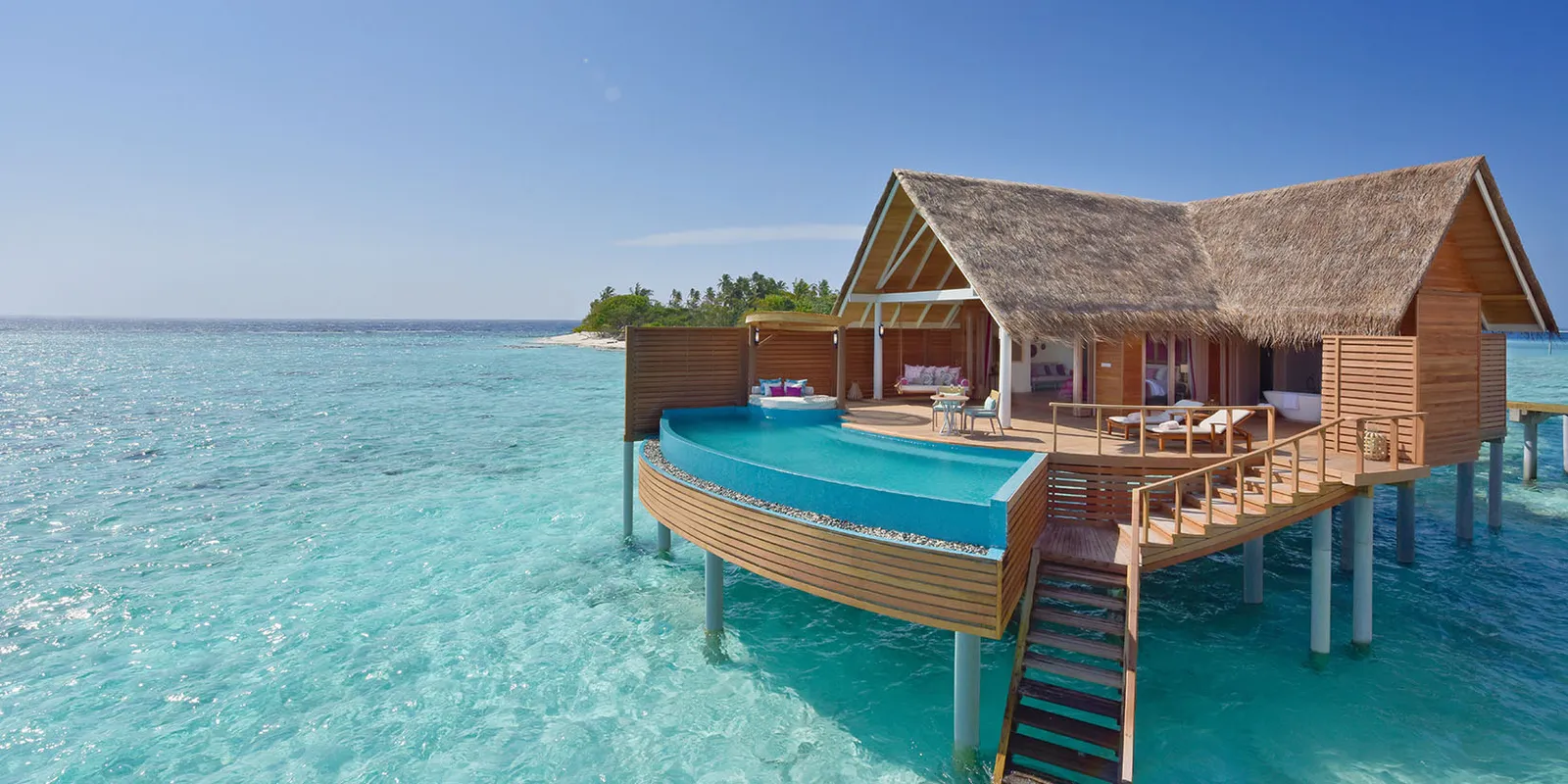 A Water Pool Villa on stilts, the pool on its deck and steps into the lagoon