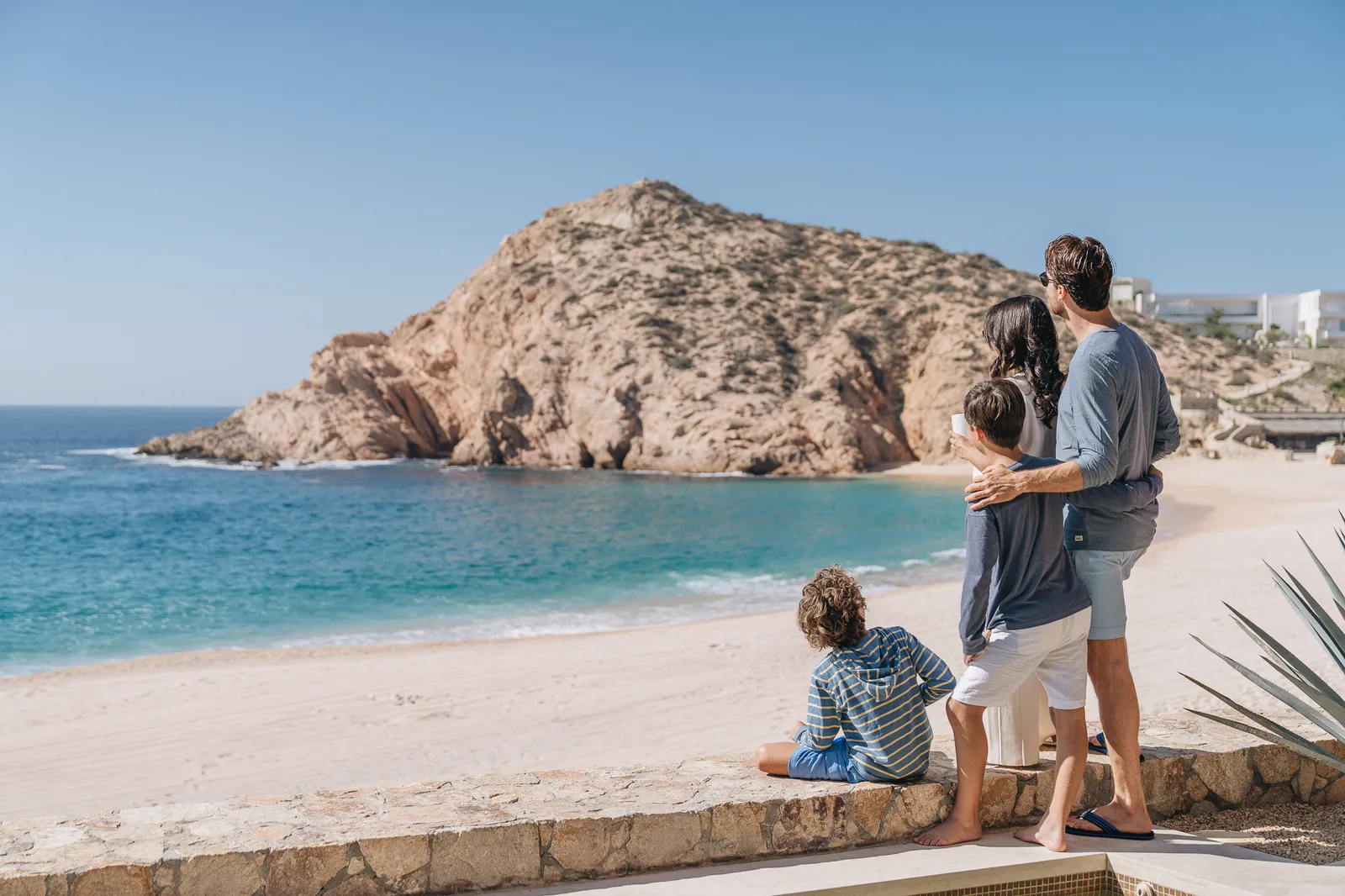 Una famiglia guarda la baia dal muretto sopra la spiaggia