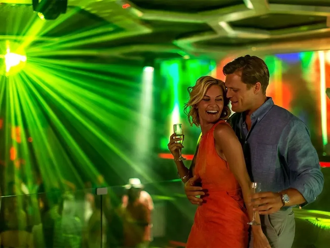 A couple dancing under green lights at Noir
