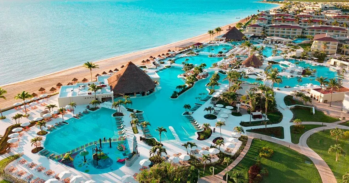 Sunrise’s pools between palms, palapa roofs and the beach at Moon Palace Cancun
