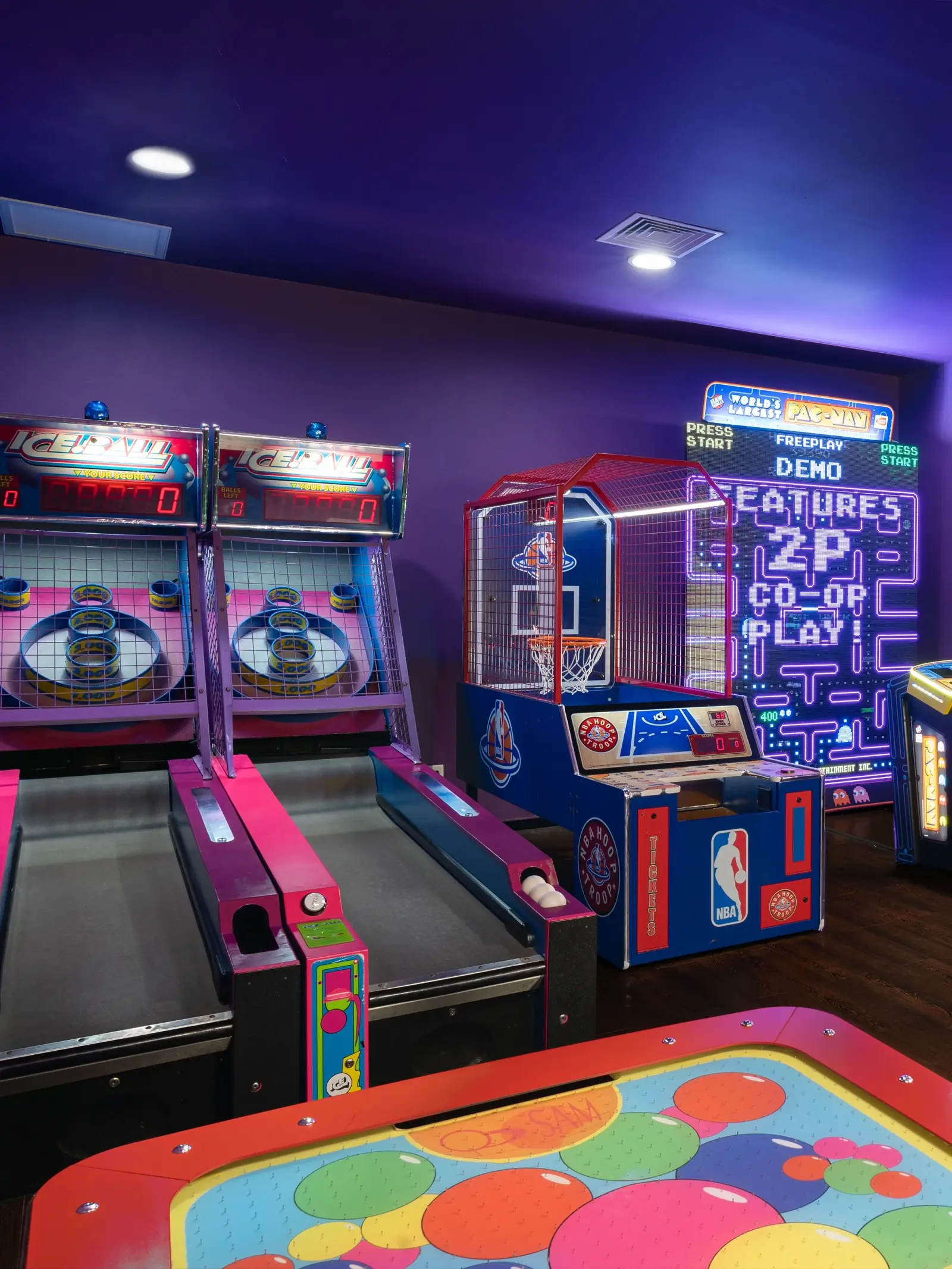 Arcade machines under colourful lights in the Playroom