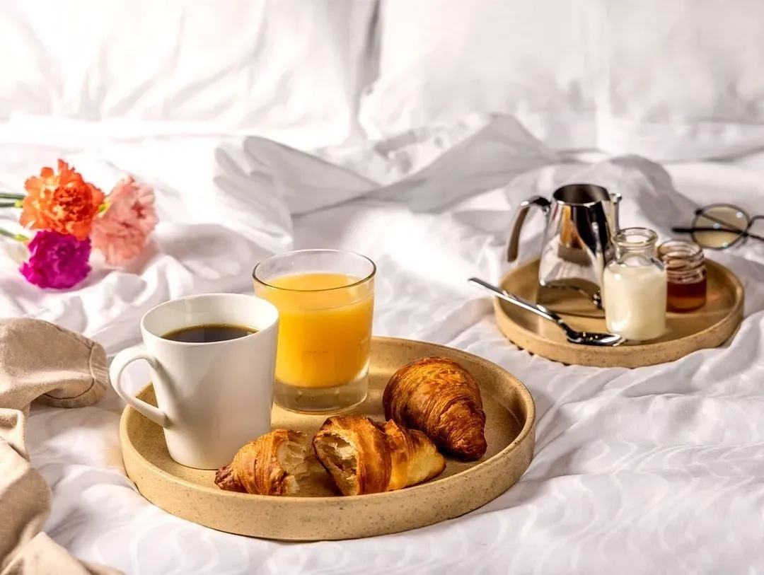 Breakfast tray with coffee, juice and croissants on a bed