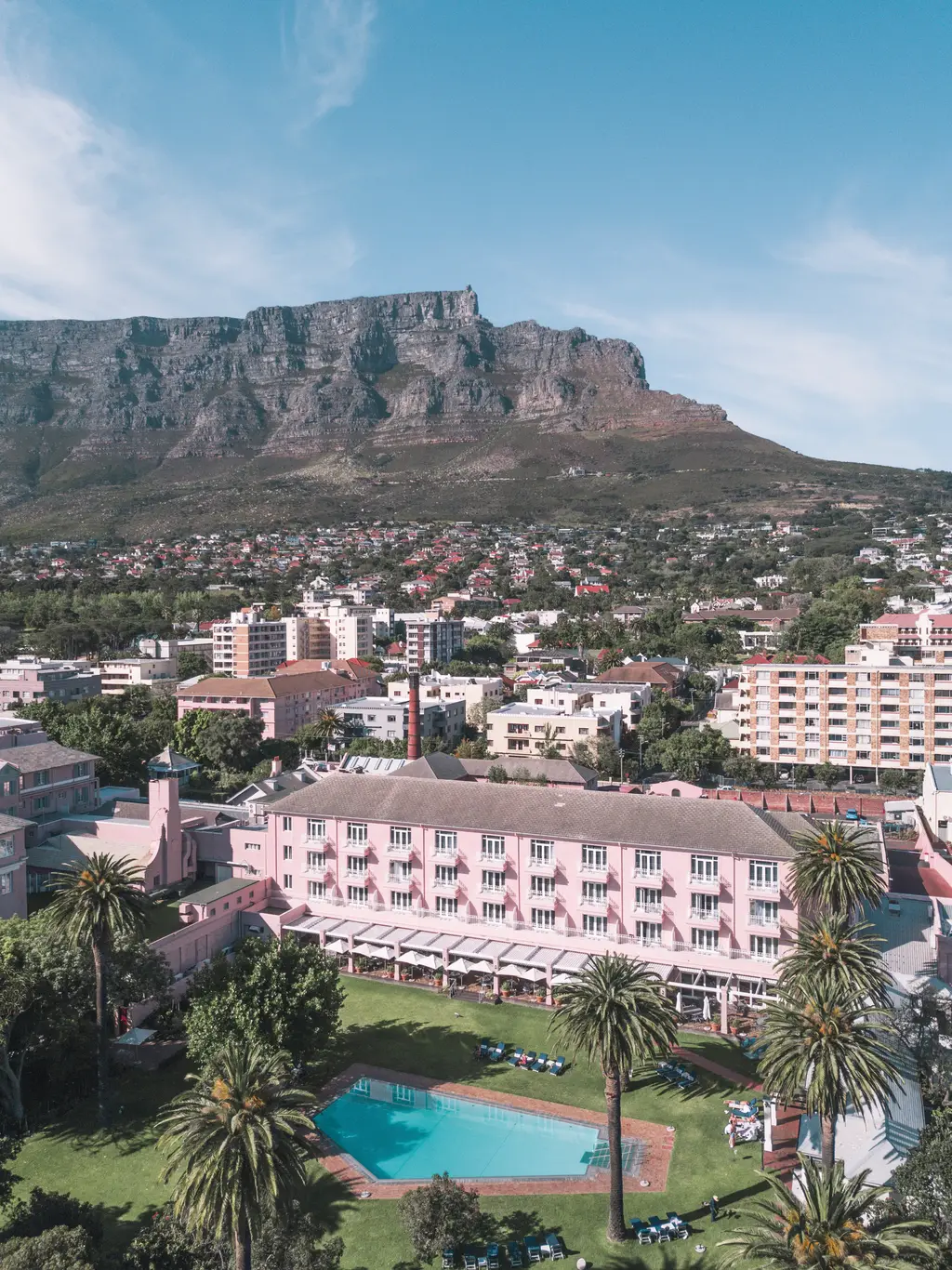 The hotel from above, the blue pool among palms and pink roofs