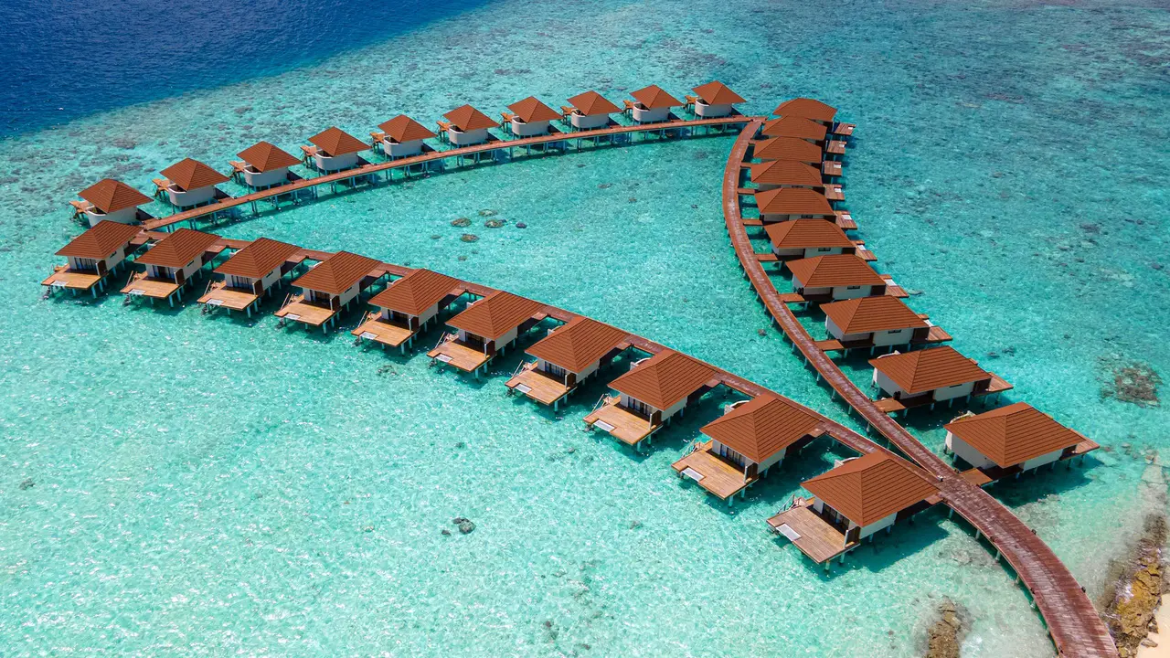 The 34 water bungalows from above, on stilts along 2 fanned walkways over the turquoise lagoon.