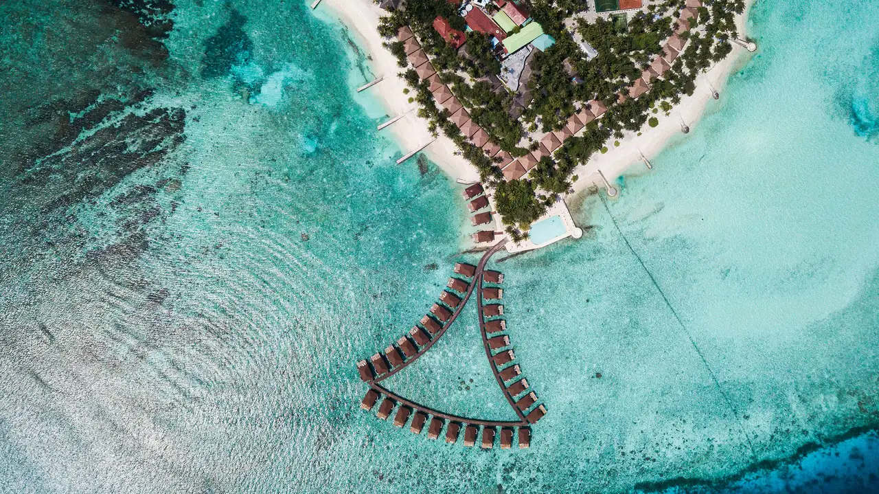 The island’s northern tip from above, with the fan of water bungalows over the reef and the pool on the sea.