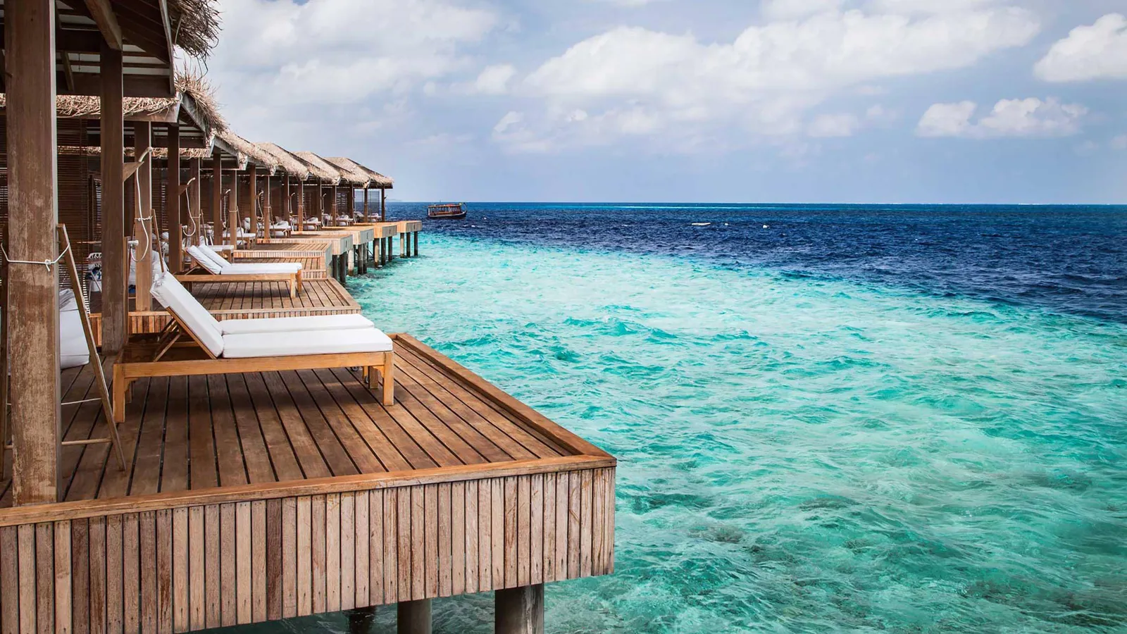 The decks of the water bungalows in a row, loungers above the clear lagoon.