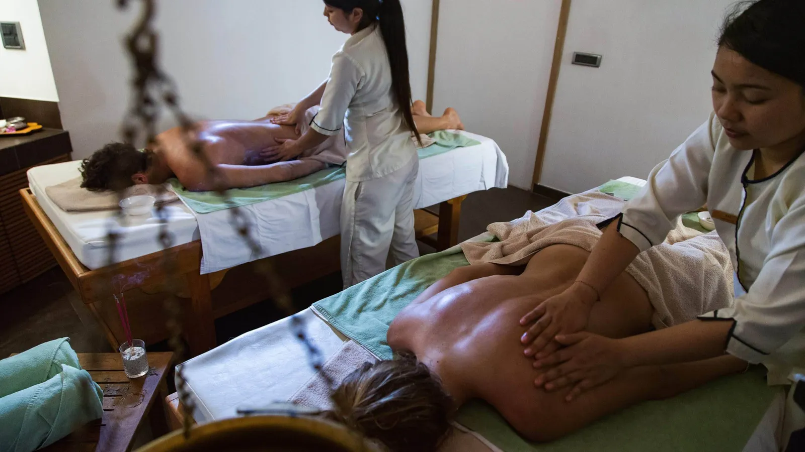 2 guests on spa tables during a massage, with 2 therapists in white.