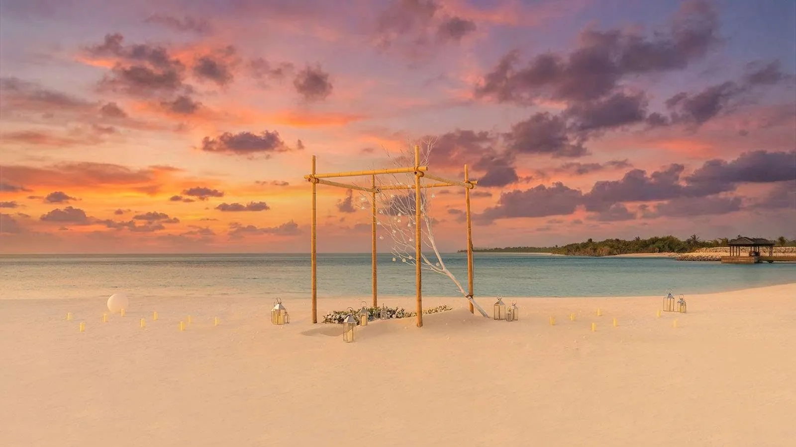 Un tavolo per 2 sulla spiaggia al tramonto, sotto un arco di legno con le lanterne e le altalene.
