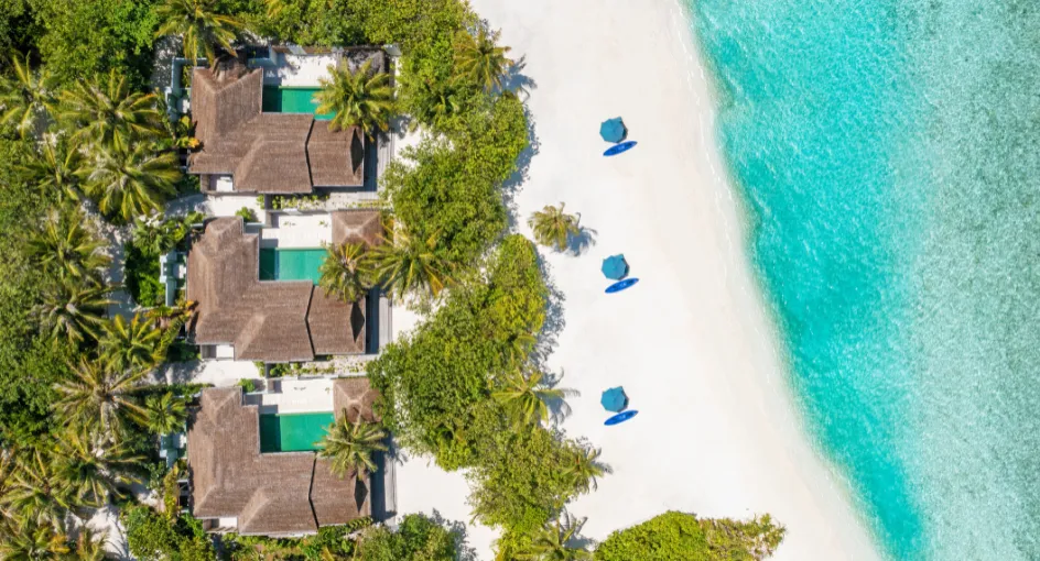 3 Beach Houses from above, each with its pool in the greenery, and the beach with parasols on the lagoon.
