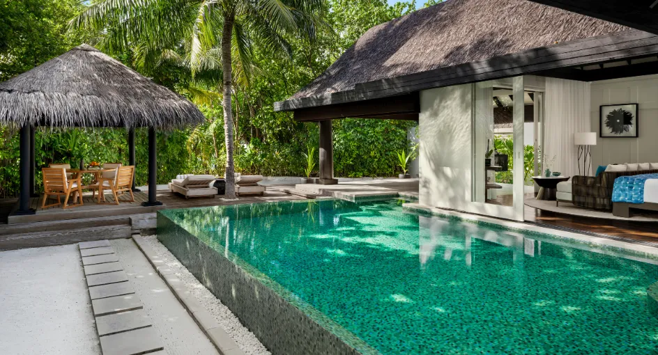 The Beach House pool between the garden and the thatched pavilion, the bedroom open on to its edge.