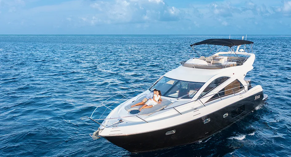 A white yacht on the open sea, a guest stretched out on the bow.