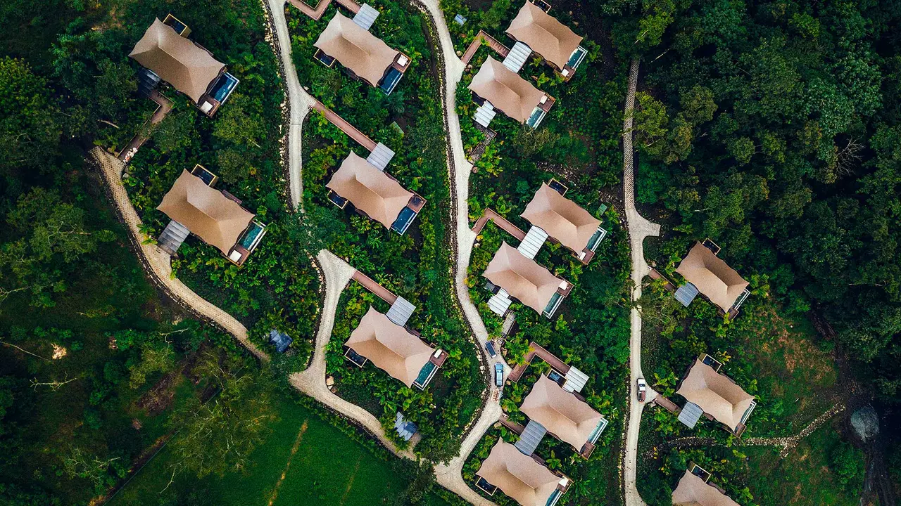 An overhead view of tents and paths among the trees