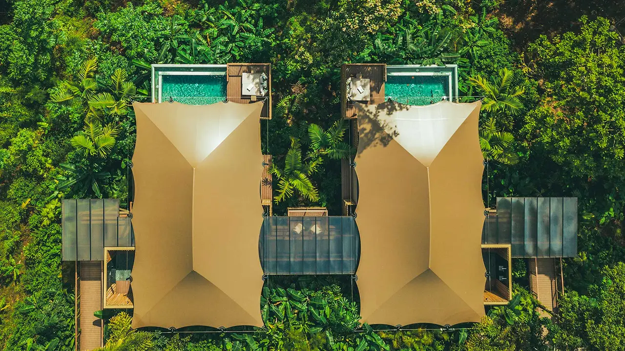 Connected tents seen from above, with a walkway and pools