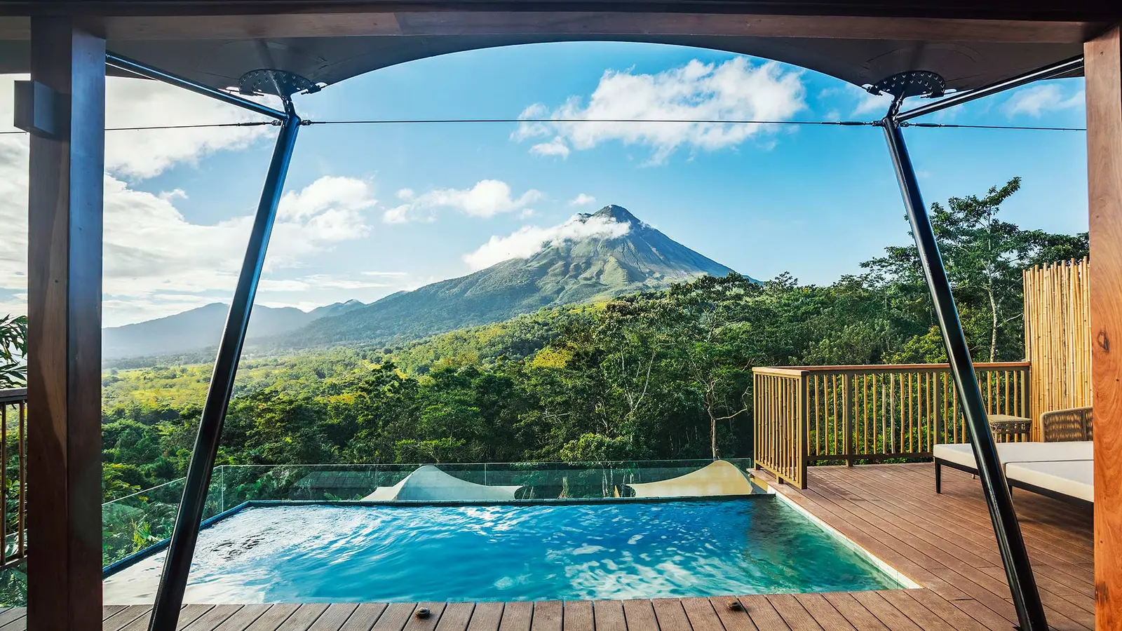 A tent’s pool and terrace, with Arenal Volcano beyond the forest