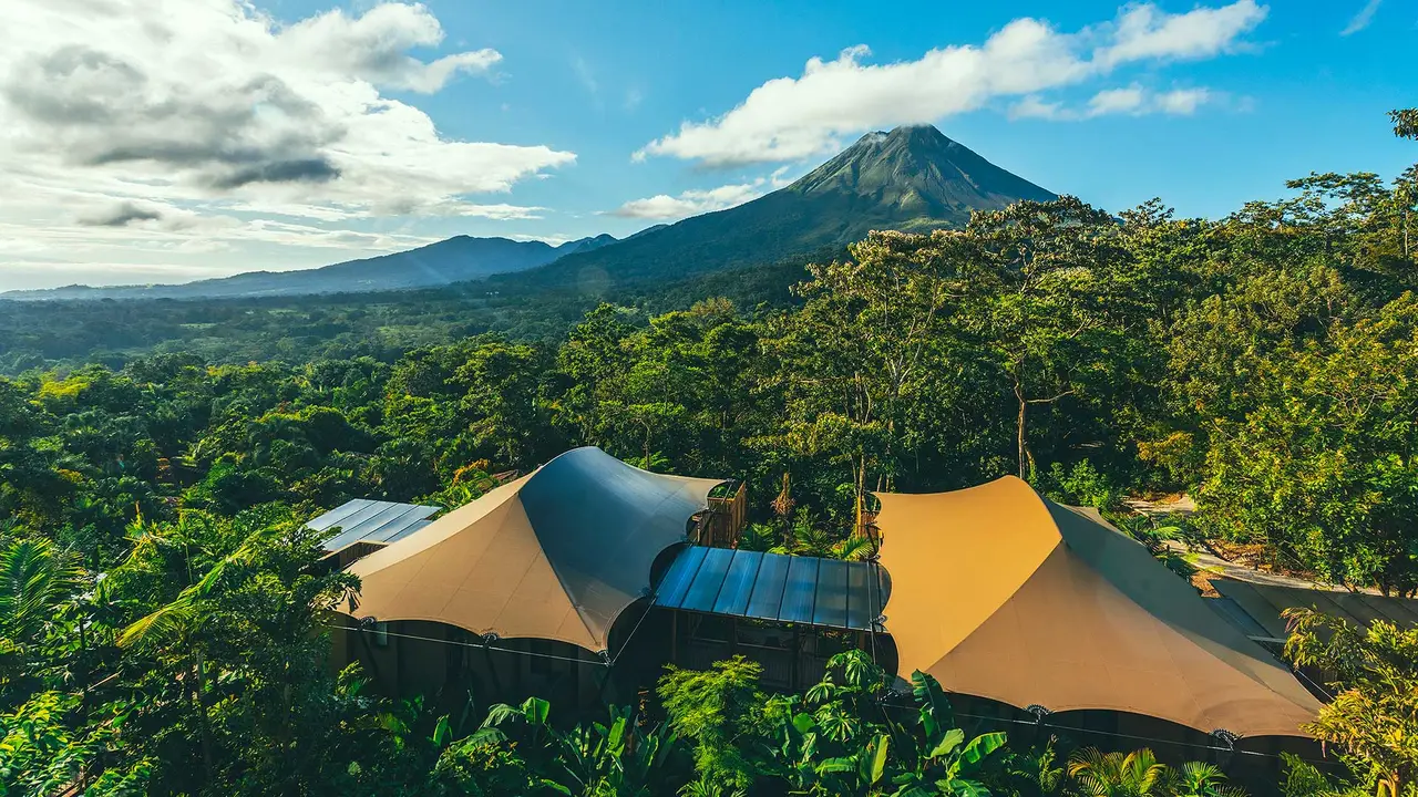 Tent roofs among the trees, with Arenal Volcano in the background