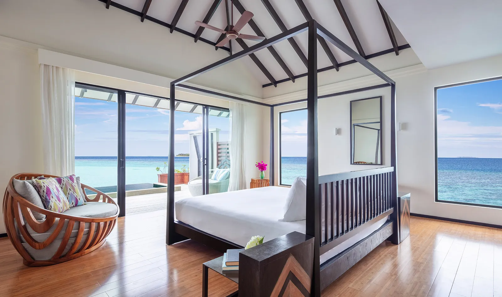 The water suite’s bedroom: the four-poster bed, an armchair and windows onto the sea on 3 sides.
