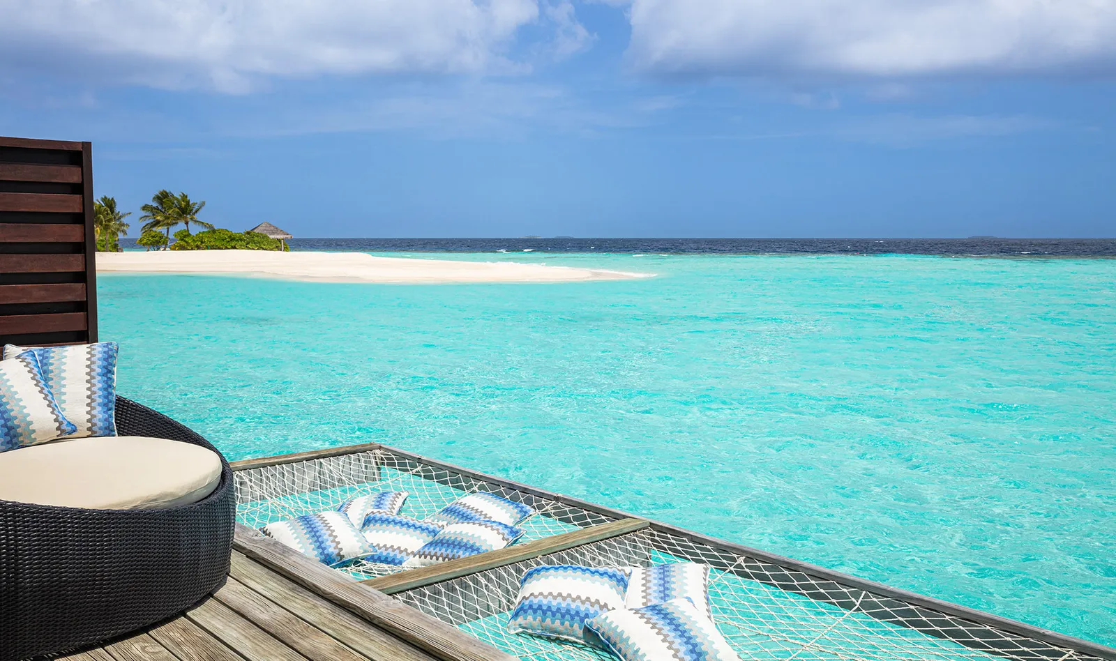 The net hammock on a water villa’s deck, hanging over the turquoise lagoon.