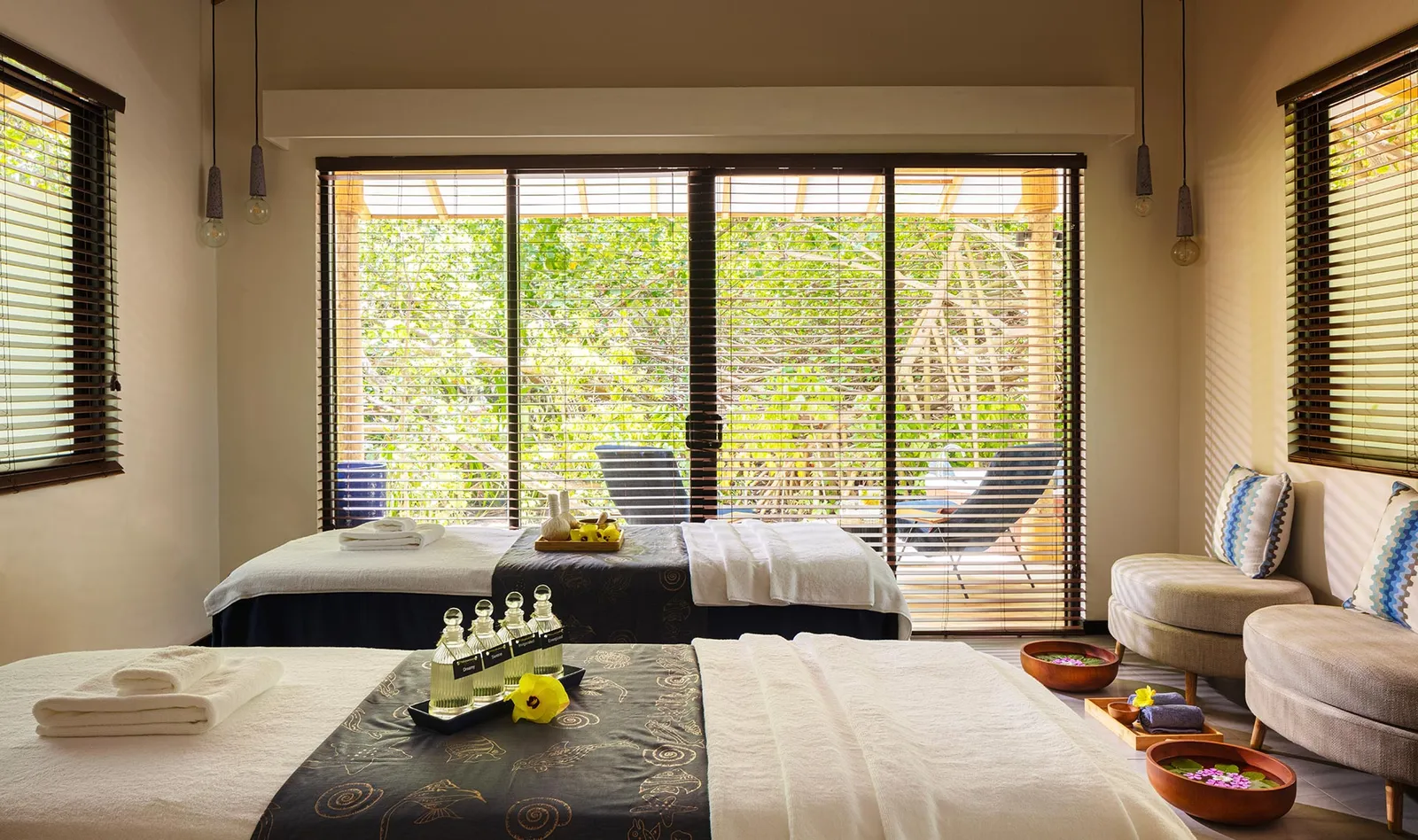 A spa treatment room with 2 massage beds and the glass doors open onto the garden.