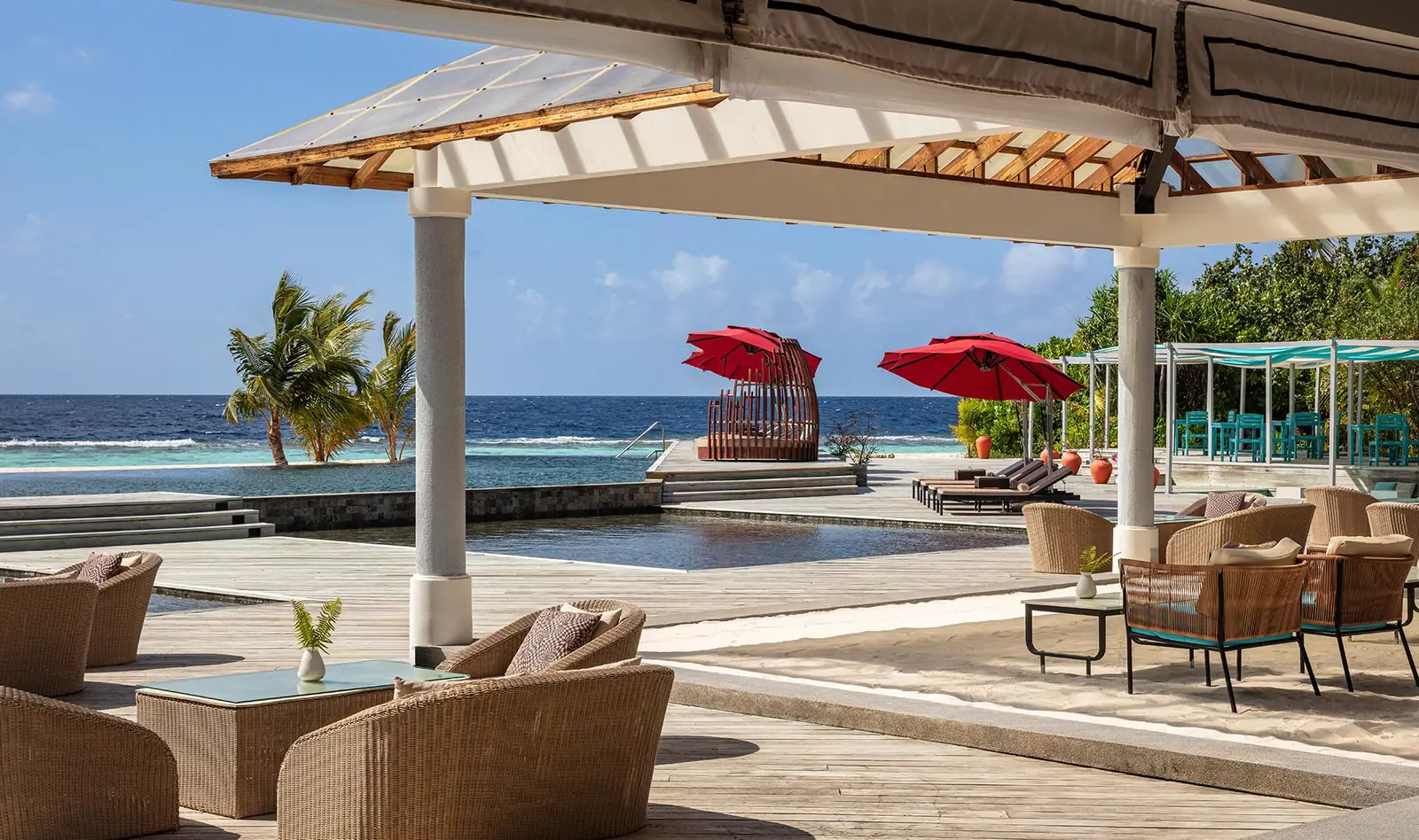 Thari Bar by the pool: wicker armchairs under the pavilion and red parasols over the water.