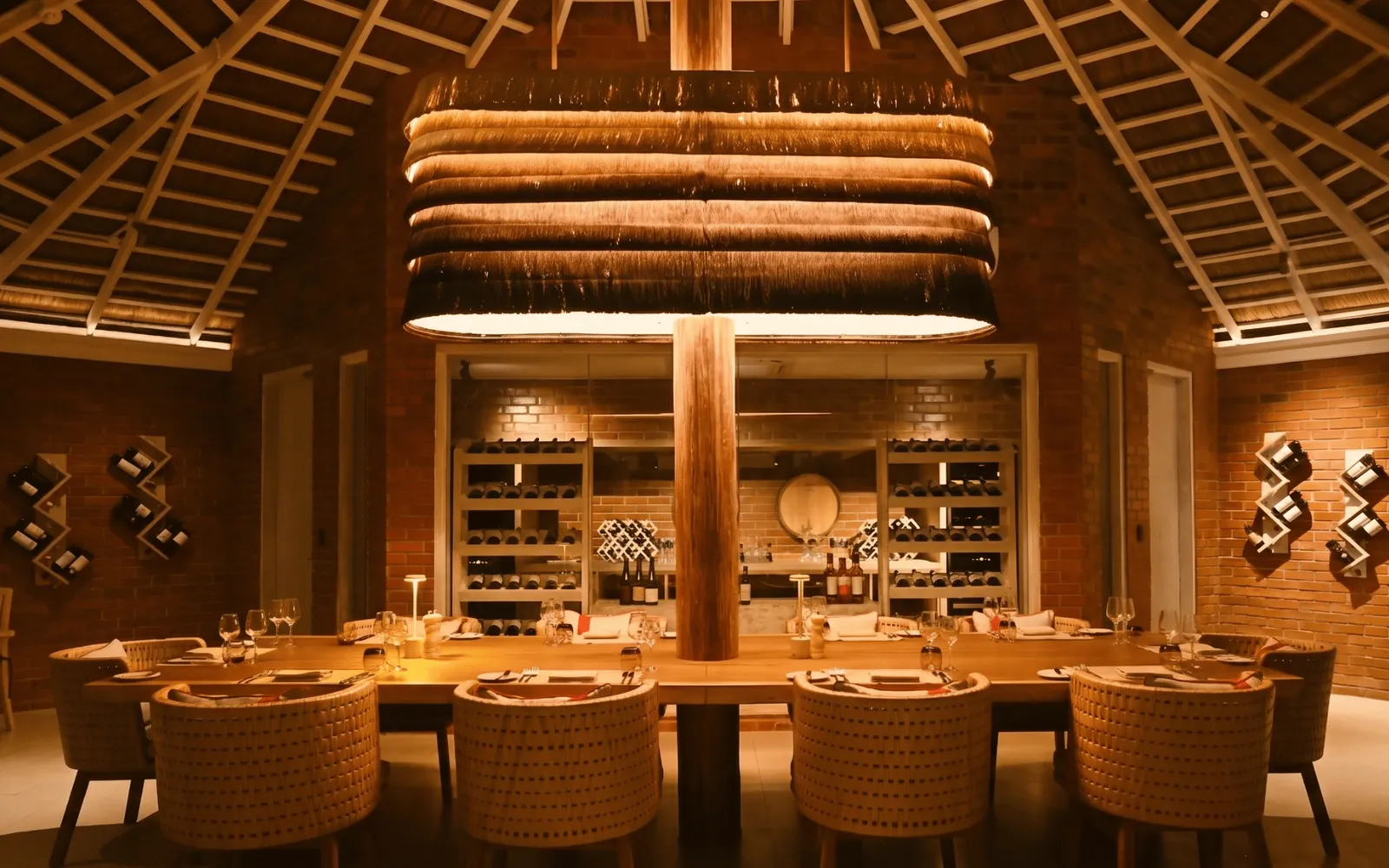 Caravela’s dining room: the long laid table, the wicker chairs, the wine wall and the radiating timber ceiling.