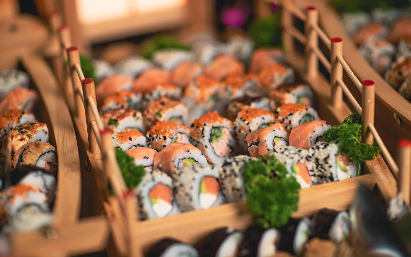 Jumla’s buffet: rows of sushi on a small timber boat, among green garnish.
